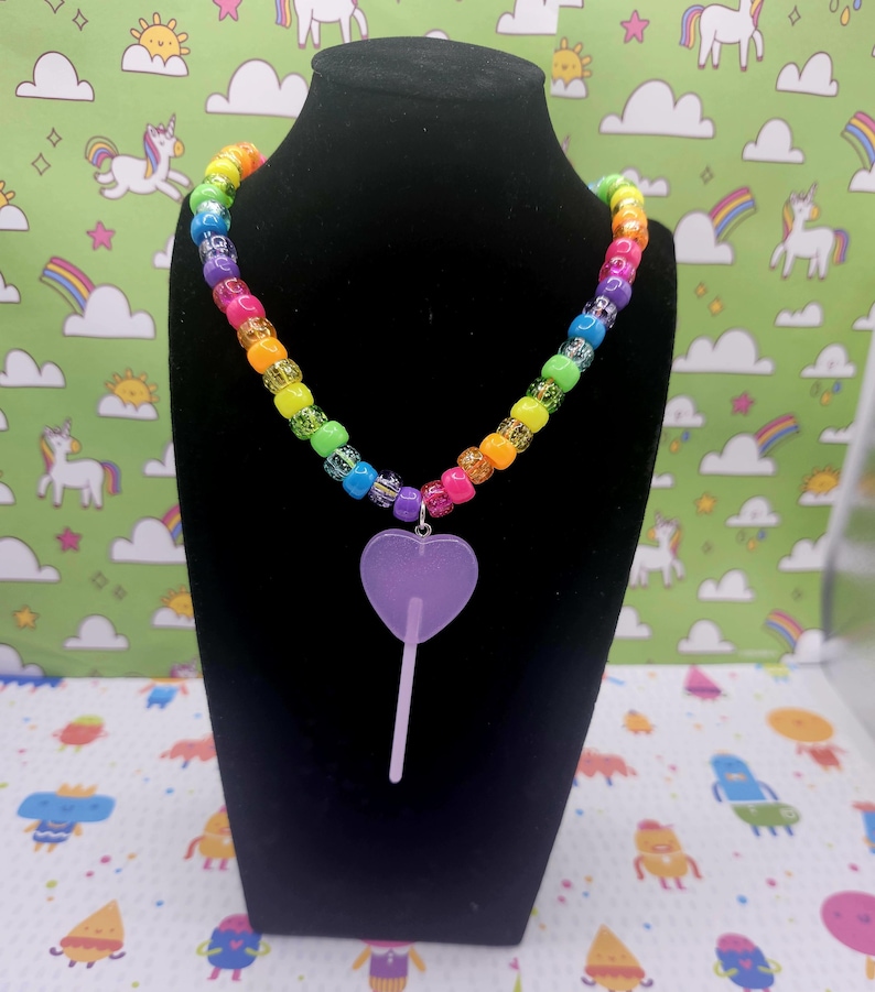 A neck model is wearing the purple lollipop necklace