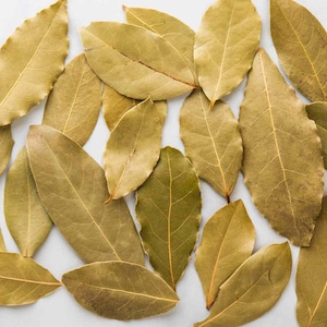 May include: A collection of dried bay leaves, a common spice used in cooking. The leaves are a light brown color and have a slightly wrinkled texture.