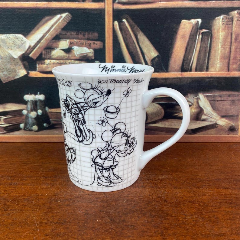 Puede incluir: Taza de cer&aacute;mica blanca con bocetos negros de Minnie Mouse sobre un fondo de cuadr&iacute;cula. La taza tiene un asa curva y las palabras "Minnie Mouse" y "Don Townley-7/1/91" est&aacute;n escritas en el borde.