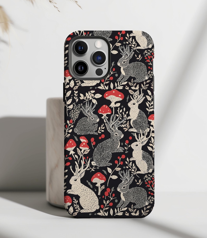 May include: Black phone case with a white and red pattern of stylized rabbits and mushrooms.
