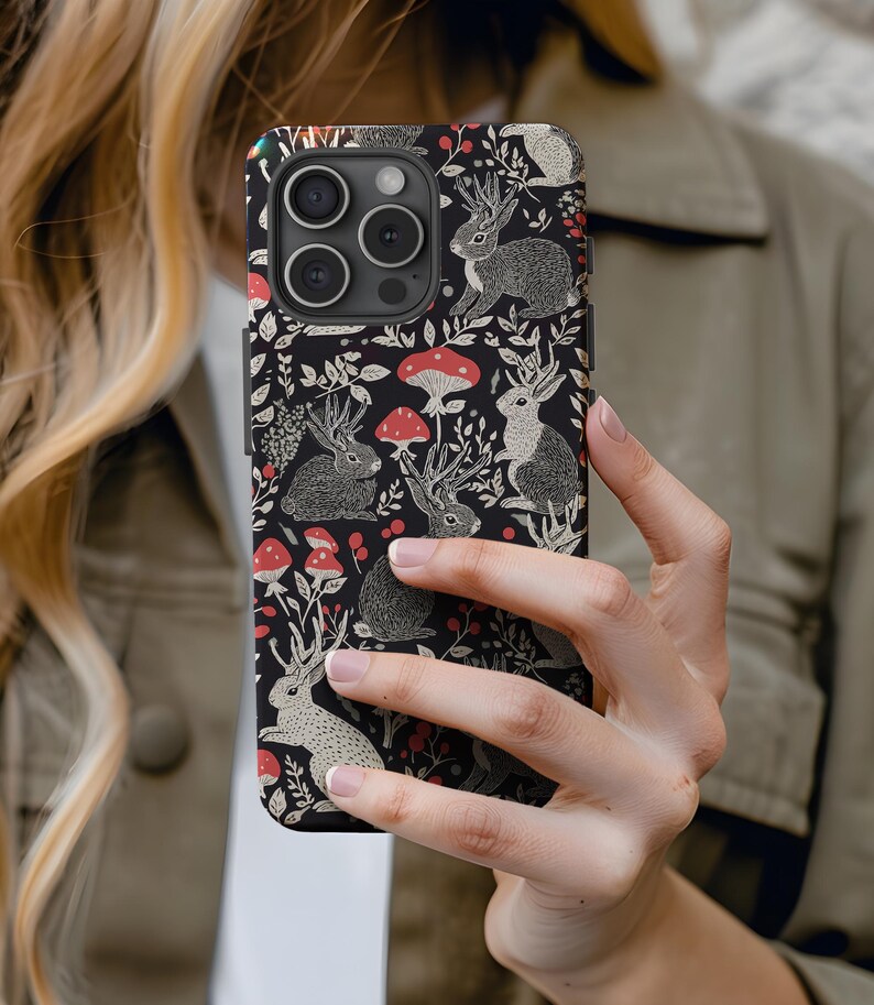 May include: A black phone case with a repeating pattern of white rabbits, red mushrooms, and green leaves.