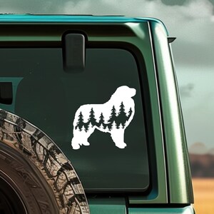 May include: White vinyl decal of a Pyrenean Mountain Dog silhouette with a forest scene inside the dog's body. The decal is on the back window of a green SUV.