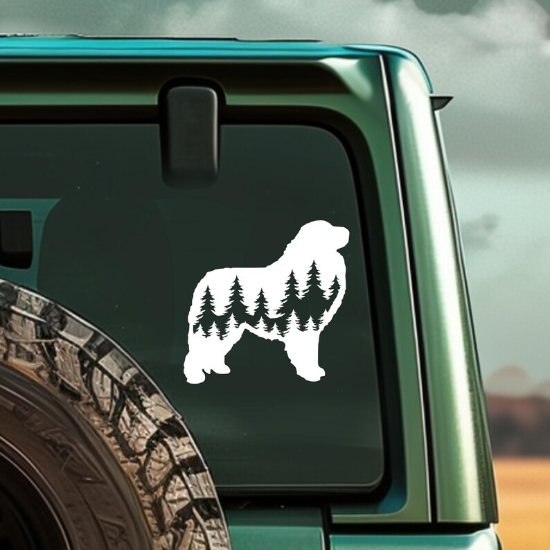 May include: White vinyl decal of a Pyrenean Mountain Dog silhouette with a forest scene inside the dog's body. The decal is on the back window of a green SUV.