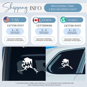 May include: A white vinyl decal in the shape of the state of Alaska featuring a silhouette of pine trees inside the border. The decal is shown applied to the rear window of a vehicle, displaying the design against the dark glass surface.
