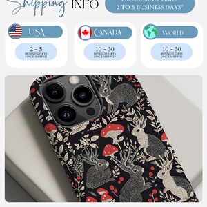 May include: A black phone case with a pattern of white rabbits, red mushrooms, and green leaves. The phone case is designed for an iPhone with a camera lens cutout.