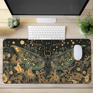 May include: A black and gold mousepad with a large, detailed illustration of a moth with red eyes. The moth is surrounded by a floral pattern with gold accents.