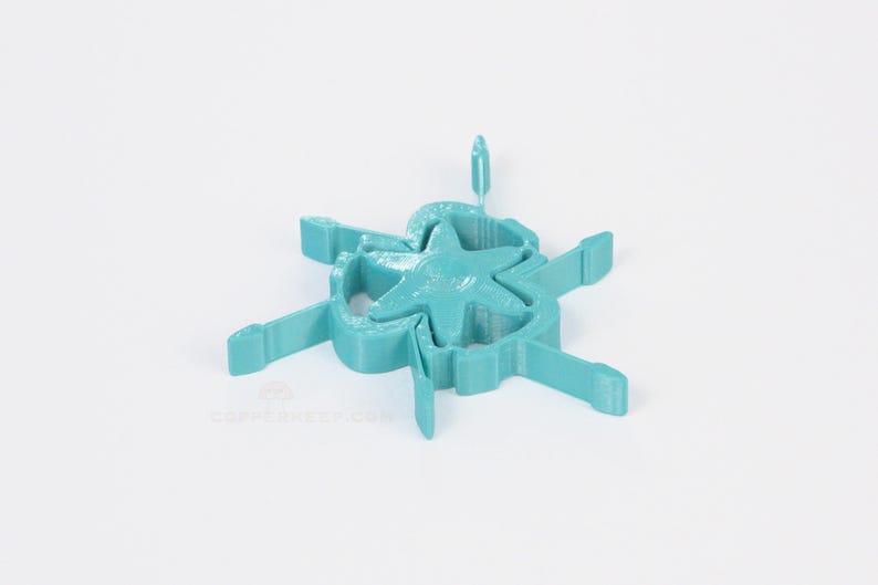 Pu&ograve; includere: Oggetto turchese stampato in 3D con una stella al centro, circondato da un design circolare con bracci rettangolari. L'oggetto &egrave; probabilmente decorativo o un componente di un design pi&ugrave; ampio. Misure in centimetri.