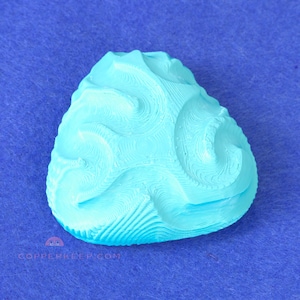 May include: A light blue, teardrop-shaped object with a textured, swirling pattern. The object is set against a blue background. The text "COPPERKEEP.COM" is visible at the bottom.