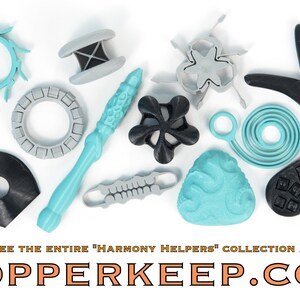 Pu&ograve; includere: Un assortimento di oggetti stampati in 3D in varie forme e colori, tra cui turchese, grigio e nero. La collezione presenta disegni geometrici, tra cui una stella, una spirale e una forma a bacchetta. Il testo sull'immagine recita "SEE THE ENTIRE 'HARMONY HELPERS' COLLECTION AT COPPERKEEP.COM."