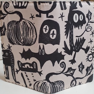 May include: A black and white fabric with a Halloween theme. The fabric features pumpkins, bats, ghosts, and other spooky creatures. The fabric is perfect for crafting projects, such as bags, pillows, and quilts.