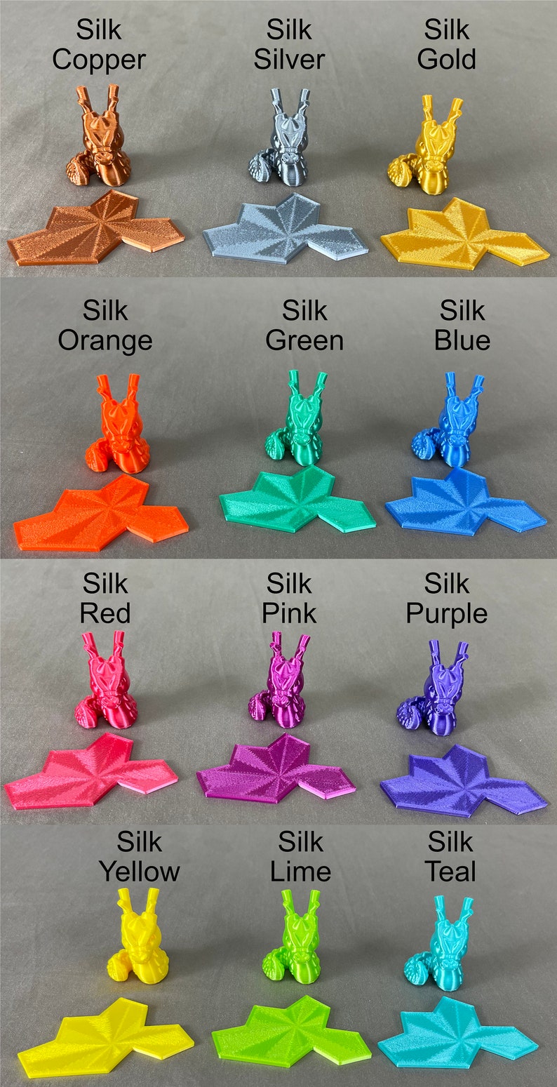 May include: A set of 12 3D printed dragon figurines in various colors, including copper, silver, gold, orange, green, blue, red, pink, purple, yellow, lime, and teal. Each figurine is sitting on a hexagonal base.