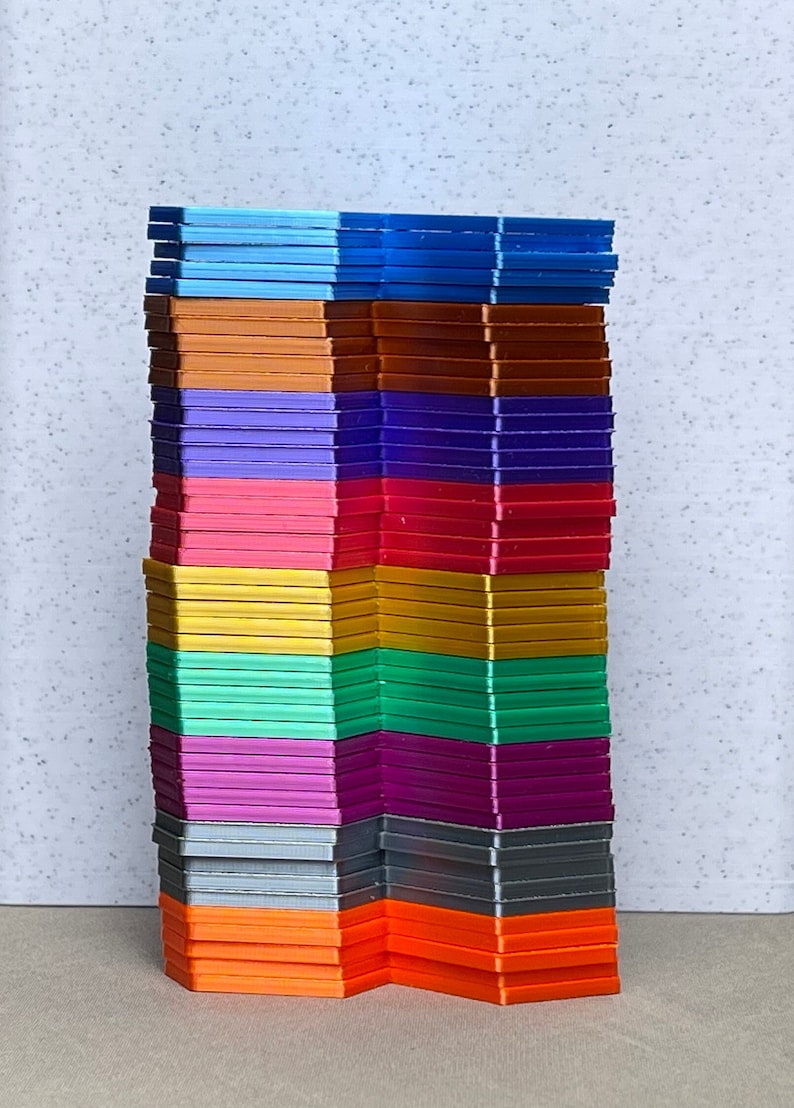 May include: A stack of colorful plastic building blocks in various shades of blue, orange, purple, pink, yellow, green, and gray. The blocks are arranged in a staggered pattern, creating a visually appealing and playful design.