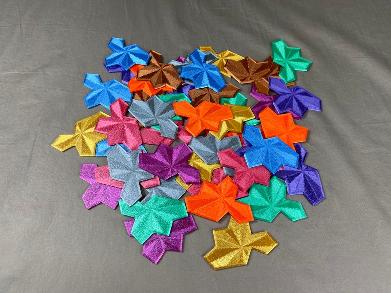 May include: A collection of colorful, star-shaped fabric patches. The patches are made of a variety of materials, including felt, velvet, and satin. They are all different sizes and shapes, and they are arranged in a random pattern.