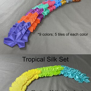 May include: Two sets of colorful, geometric tiles arranged in a curved pattern. The top set is labeled "Standard Silk Set" and includes 9 colors with 5 tiles of each color. The bottom set is labeled "Tropical Silk Set" and includes 3 colors with 15 tiles of each color.