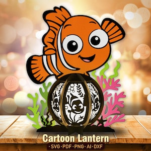 May include: A decorative cartoon lantern featuring an orange and white clownfish design. The lantern has a black frame with a cut-out design and is accompanied by green and pink coral accents. The text "Cartoon Lantern" is displayed at the bottom.