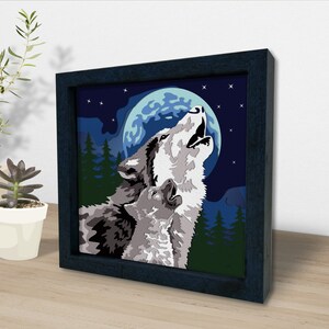 May include: A framed painting of two wolves howling at the moon. The wolves are gray and white, and the moon is a pale blue. The background is a dark blue with stars.