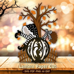 May include: A multi-layered paper cut design featuring a brown tree with orange leaves, a black and white polka dot hooded figure with striped legs, a broom, and a central lantern silhouette showing a witch and cat behind a wooden fence.