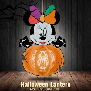 Puede incluir: Una linterna de Halloween con forma de calabaza con una cara de Mickey Mouse y un lazo. La calabaza es naranja y tiene una araña negra a cada lado. La linterna está hecha de papel y está diseñada para ser iluminada desde el interior.