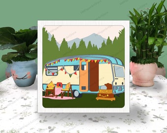May include: A papercraft model of a vintage camper van parked in a forest setting. The camper is decorated with colorful bunting and has a blue and yellow exterior. The scene includes a picnic table with chairs and a jack-o-lantern.