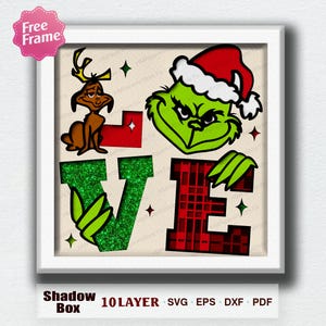 May include: A framed shadow box featuring the Grinch and Max with the word "LOVE". The "V" is green glitter, the "E" is red plaid, and the "L" and "O" are red. The Grinch wears a Santa hat. The frame has a pink "Free Frame" sticker.