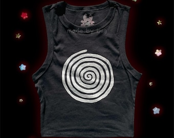 Pode incluir: Top curto sem mangas preto com um design de espiral branco. O texto "made by bug" está impresso na frente. A parte superior é rodeada por decorações em forma de estrela.