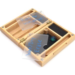 May include: Wooden box with a hinged lid, containing three clear plastic cards with handwritten labels: "Roll for Initiative", "Wet/Dry Erase", and "Dice". A single blue and green dice is visible in the box.