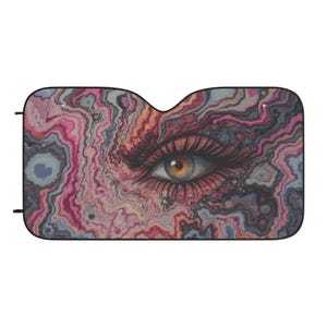 Può includere: Parasole per auto con un'illustrazione dettagliata di un occhio con lunghe ciglia e uno sfondo colorato e marmorizzato nei toni del rosa, viola e arancione. L'occhio ha un'iride dorata.