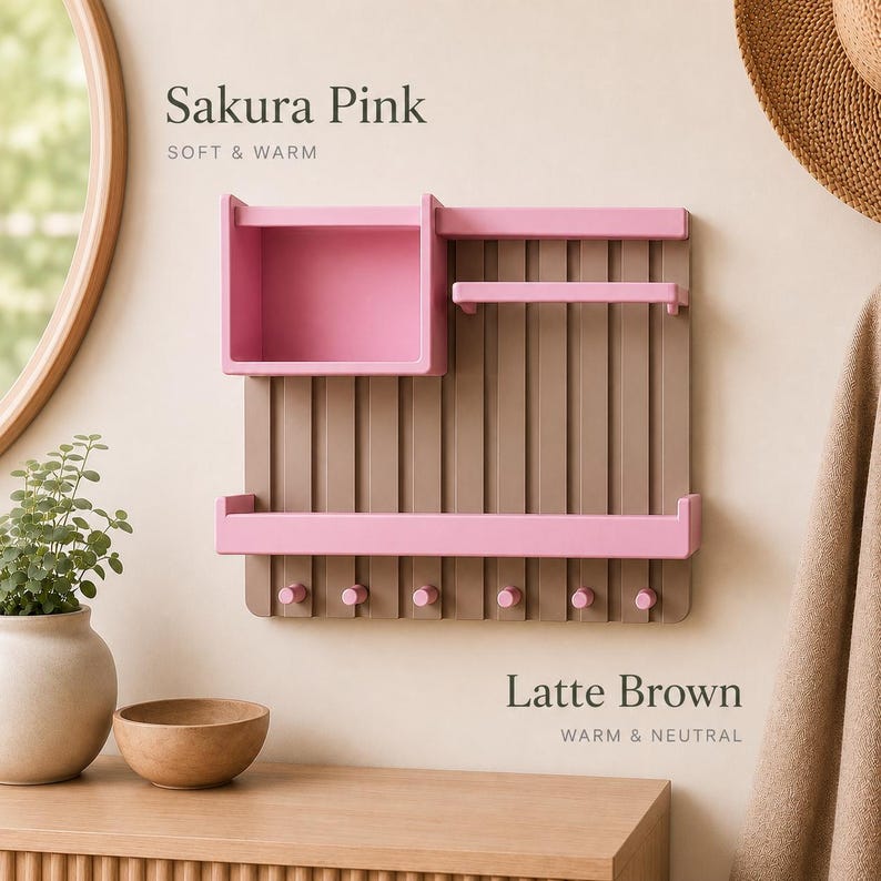 May include: A wall-mounted organizer featuring a vertical slat design in latte brown with sakura pink accents. It includes a square storage box, two horizontal shelves, and six small pegs at the bottom. The text Sakura Pink and Latte Brown is visible.