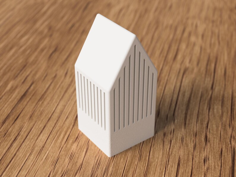 May include: A white, house-shaped decorative object with vertical lines on the sides. The object has a pitched roof and sits on a wooden surface. The design is minimalist and modern, suitable for home decor.