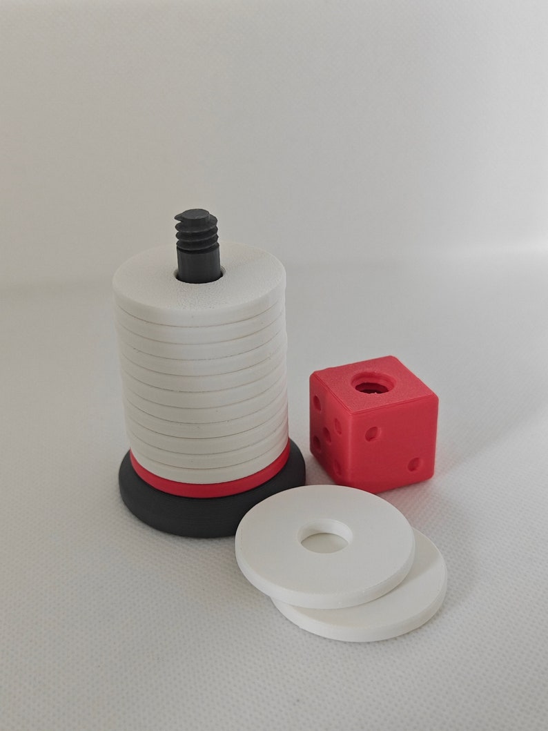 May include: A white and red stacking tower with a black base and a black screw on top. There are two white rings next to the tower and a red cube with black dots.