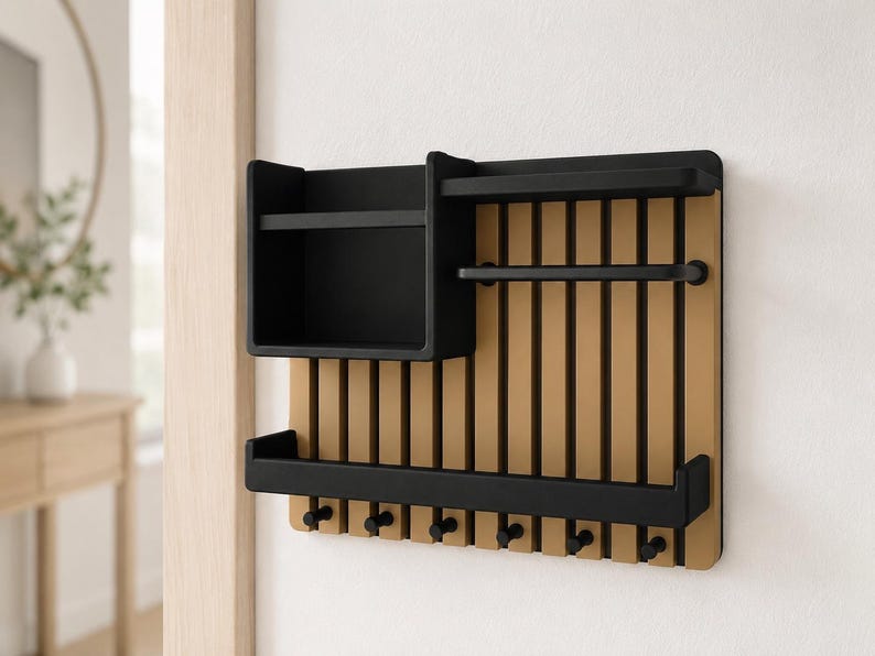May include: A wall-mounted organizer featuring a light wood-toned slatted back panel with black accents. It includes a deep rectangular storage bin, two horizontal shelves, and six small black hooks along the bottom edge for hanging items.