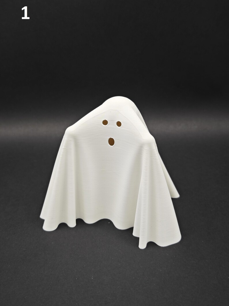 Puede incluir: Figurita de fantasma blanco con una cara simple, dos ojos y una boca, hecha de un material blanco liso.
