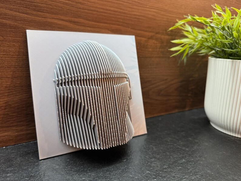 Puede incluir: Una escultura de pared de arte 3D impresa en blanco de un casco. El casco est&aacute; hecho de muchas l&iacute;neas verticales delgadas que crean un efecto texturizado.