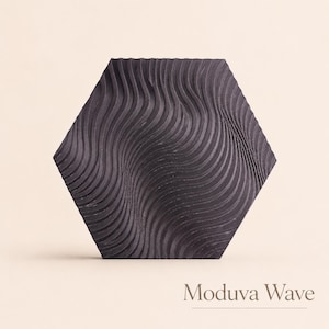 May include: A dark gray, hexagonal tile with a wave-like pattern. The tile's surface features a series of curved, parallel lines that create a textured effect. The text "Moduva Wave" is displayed at the bottom of the image.