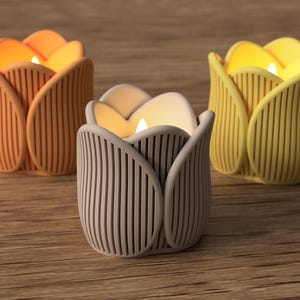 May include: Three tulip-shaped candle holders in orange, beige, and yellow, each with a lit candle inside. The holders have vertical ribbed detailing and sit on a wooden surface. The candles emit a warm, inviting glow.
