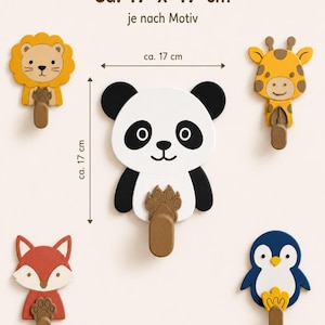 May include: Five animal-shaped wall hooks featuring a lion, panda, giraffe, fox, and penguin. Each hook includes a brown peg and measures approximately 17 x 17 inches. The text "Ca. 17 x 17 cm" and "je nach Motiv" is visible at the top of the image.