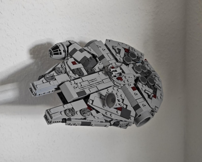 May include: A detailed model of the Millennium Falcon spaceship, constructed from interlocking building blocks. The model features a grey colour scheme with intricate detailing, including various panels, turrets, and circular elements. The spaceship is a popular item from the Star Wars franchise.