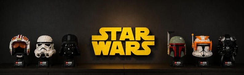 Pode incluir: Uma cole&ccedil;&atilde;o de capacetes de personagens de Star Wars, incluindo Darth Vader e Boba Fett, exibidos em uma prateleira. O logotipo amarelo "STAR WARS" est&aacute; centralizado acima dos capacetes. Cada capacete &eacute; uma r&eacute;plica detalhada, mostrando os designs ic&ocirc;nicos da franquia Star Wars.