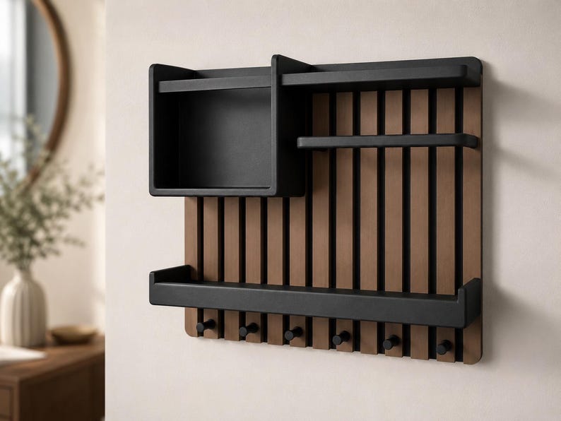 May include: A wall-mounted organizer featuring a slatted brown wood back panel with a black frame. It includes a square storage box, two horizontal shelves, and six small black hooks along the bottom edge for hanging various items.