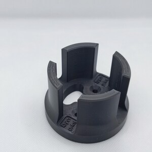 May include: A black, 3D-printed object with a circular base and four curved, vertical supports. The supports are evenly spaced around the circumference. The object has the text "layer print" on the side.