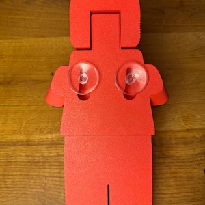 May include: Red foam figurine of a person with suction cups on the back. The figurine is shaped like a Lego person.