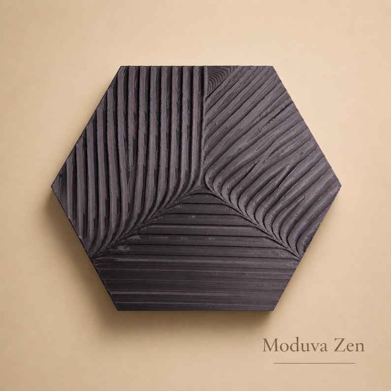May include: A dark gray, hexagonal wall art piece with a textured, carved design. The surface is divided into sections with vertical and diagonal grooves, creating a leaf-like pattern. The text "Moduva Zen" is at the bottom.