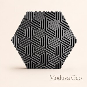 May include: A dark gray, hexagonal tile with a geometric pattern of intersecting lines. The tile's surface has a textured appearance, and the design is repeated across the entire surface. The text "Moduva Geo" is at the bottom.