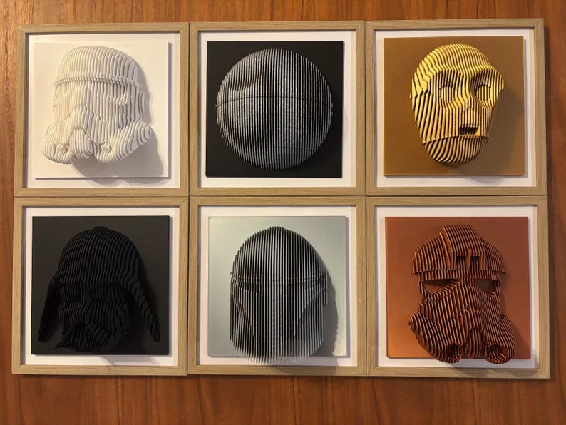 Puede incluir: Seis piezas de arte de pared enmarcadas con esculturas 3D de personajes de Star Wars. Las esculturas est&aacute;n hechas de papel y est&aacute;n pintadas en varios colores, incluyendo blanco, negro, dorado y naranja. Los marcos est&aacute;n hechos de madera y tienen un acabado marr&oacute;n claro.