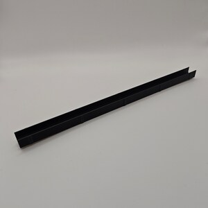 May include: A long, black, U-shaped metal channel. The channel is rectangular with a flat base and two parallel sides. The object is set against a plain white background.