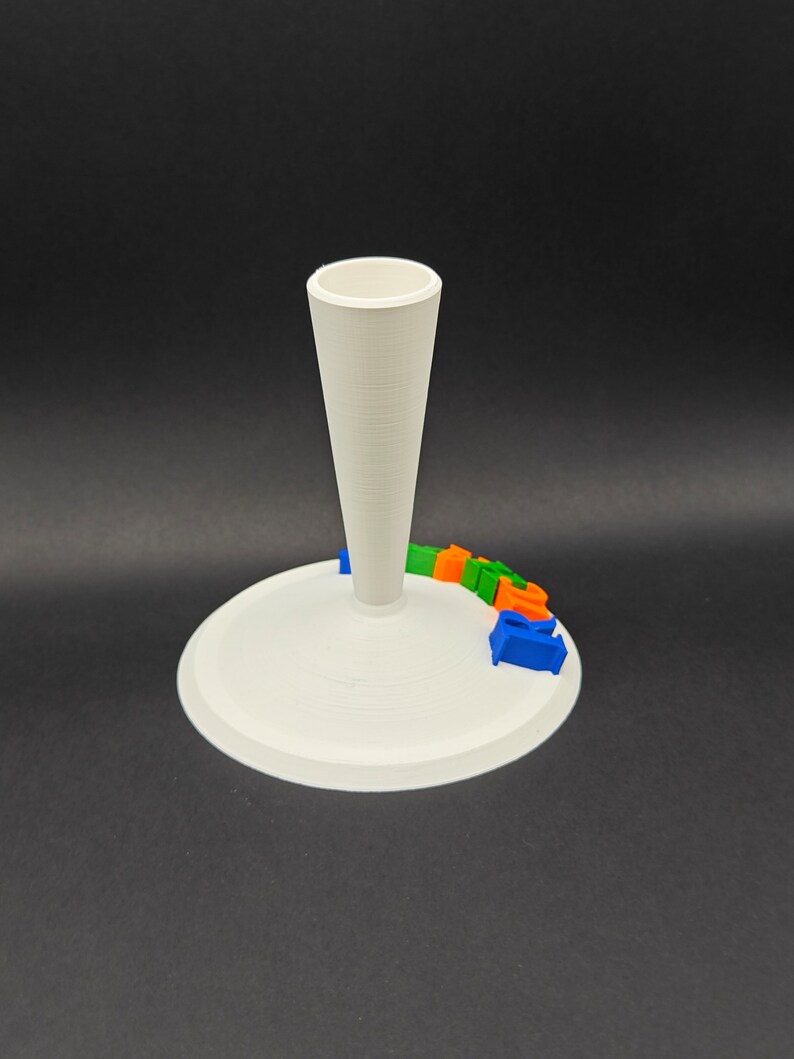 Puede incluir: Soporte blanco impreso en 3D con una parte superior en forma de cono y una base circular. El soporte tiene la palabra "GOOGLE" impresa en color alrededor de la base.