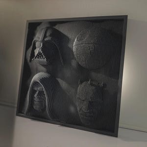 May include: A black and white framed wall art piece featuring a 3D design of various characters from the Star Wars franchise. The characters are made of layered cardboard and are displayed against a black background.