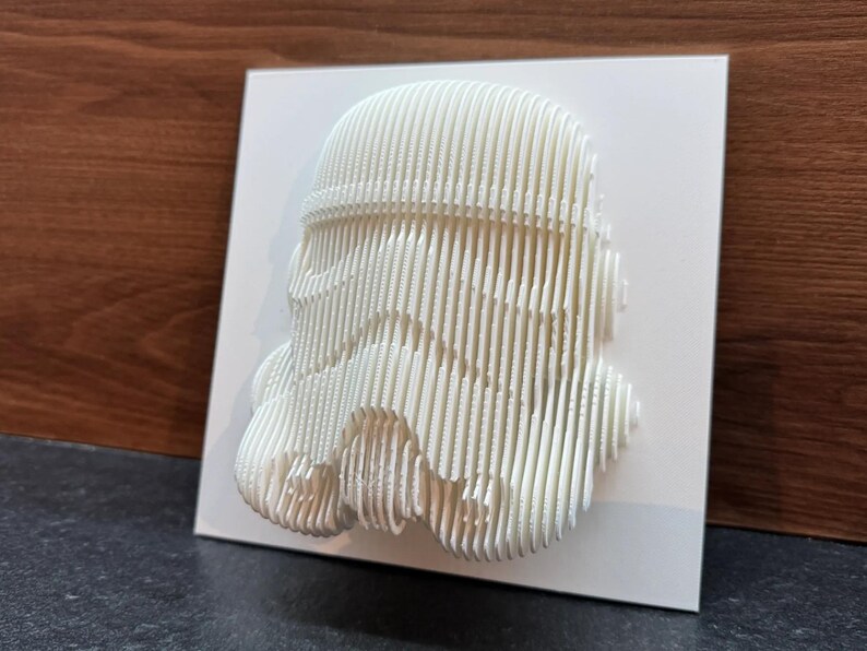 Puede incluir: Arte de pared impreso en 3D blanco de un casco de Stormtrooper de Star Wars. El casco est&aacute; hecho de l&iacute;neas delgadas y superpuestas que crean un aspecto &uacute;nico y moderno.