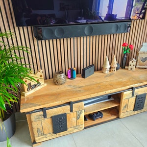 May include: A reclaimed wood TV unit with sliding doors and metal detailing. The unit has a natural wood finish and is adorned with decorative items, including a plant, ornaments, and gaming consoles. The unit is approximately 150 cm long.