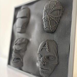 May include: A gray framed wall art piece with three 3D faces created using a layered, striped design.